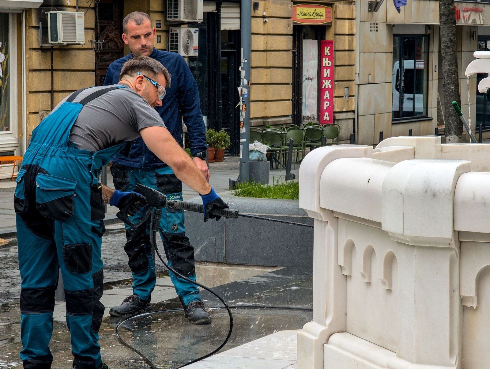 Zwei Mitarbeiter reinigen einen Brunnen mit dem Hochdruckreiniger