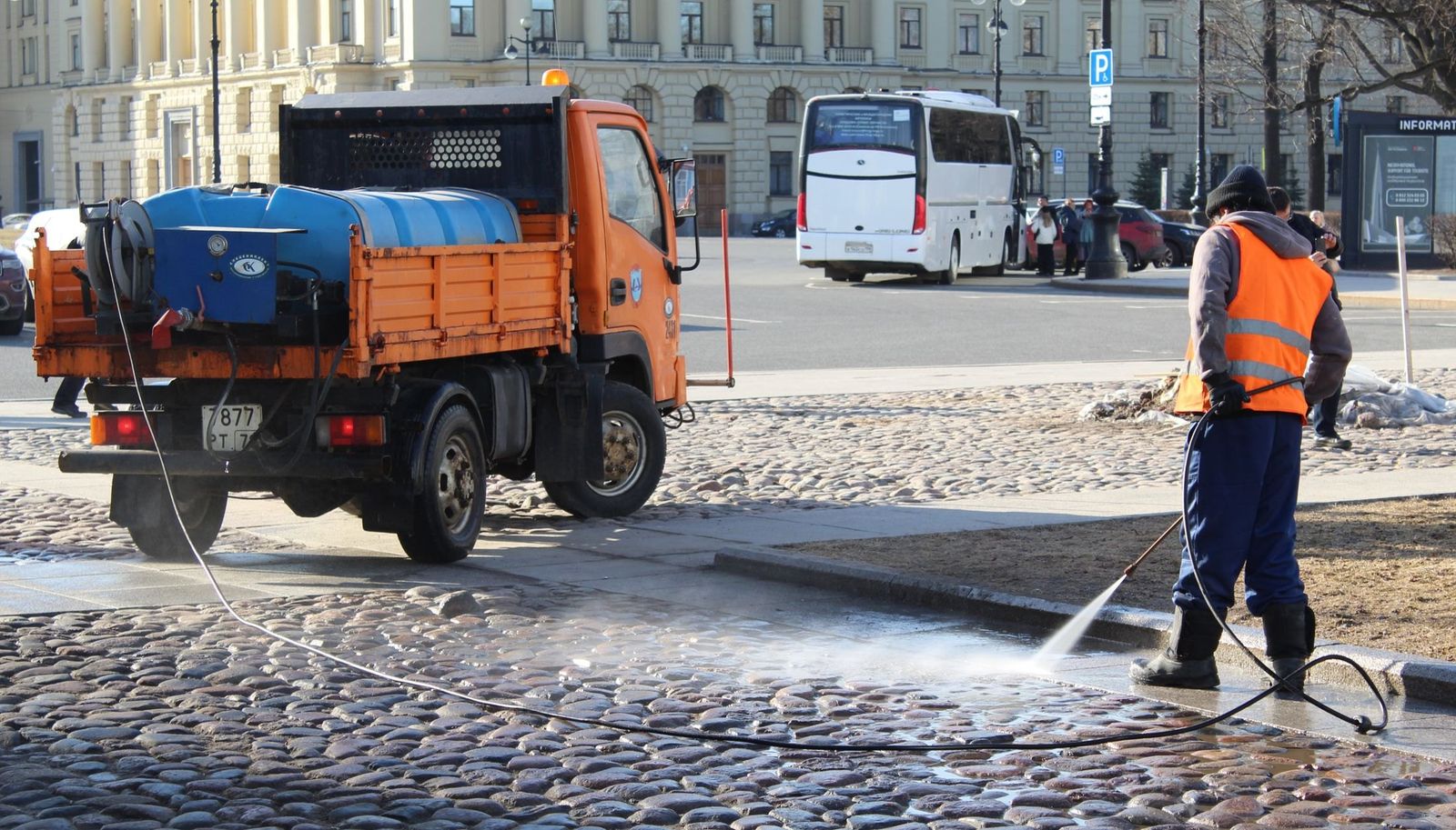 Reinigung einer Fläche mit Wasserschlauch im Sonnenlicht